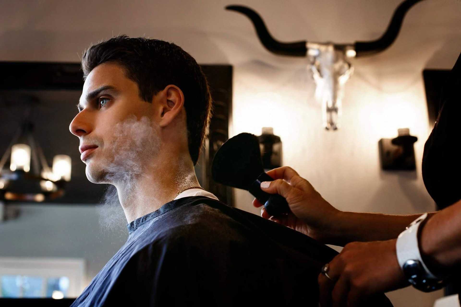 Person getting a haircut in a salon, bull skull decor on the wall.