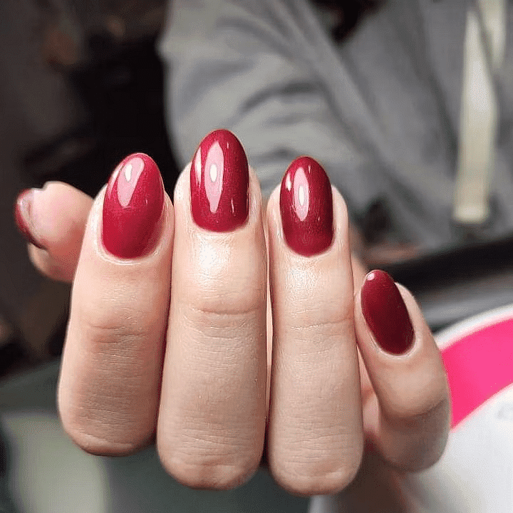 Hand with glossy dark red polished nails.