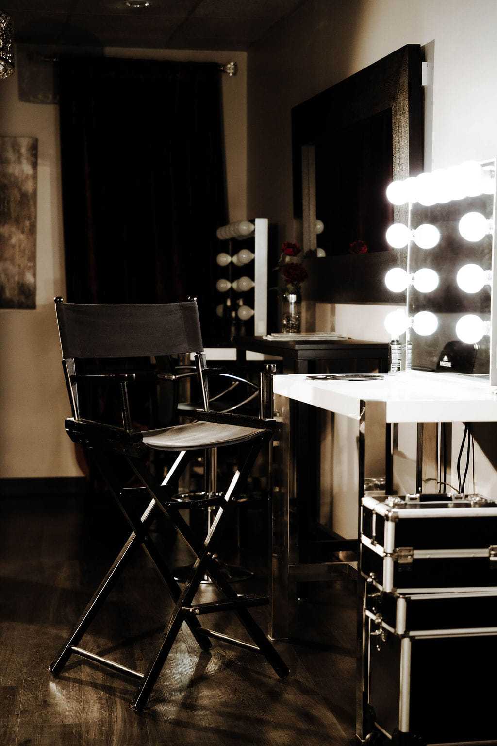 Makeup studio with director's chair and illuminated vanity mirror.