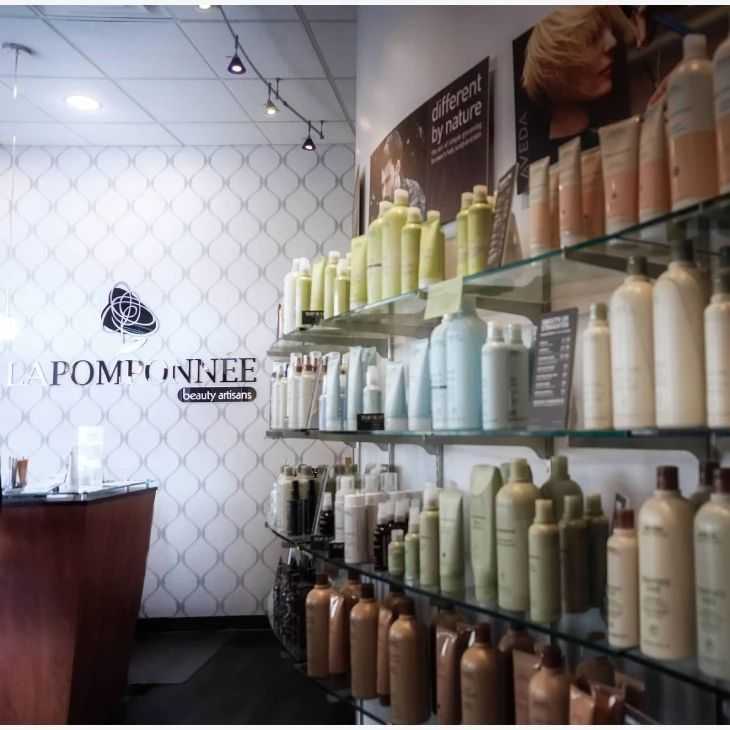 Shelves with various beauty products in a modern salon with the sign "LA POMPONNEE" on the wall.