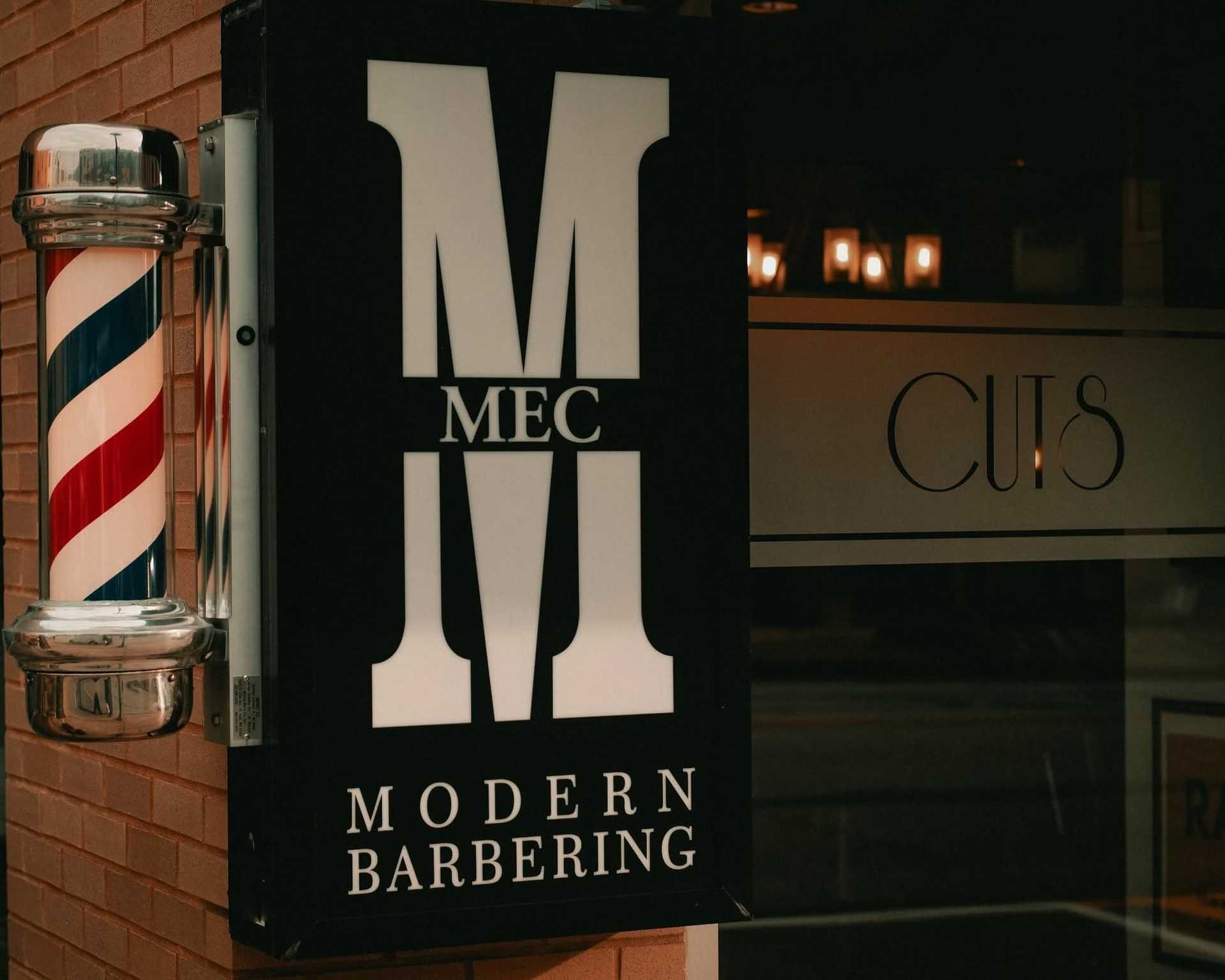 Barber shop sign with classic red, white, and blue pole outside.