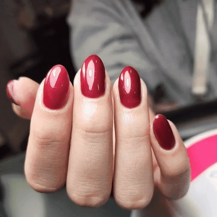Hand with glossy dark red polished nails.